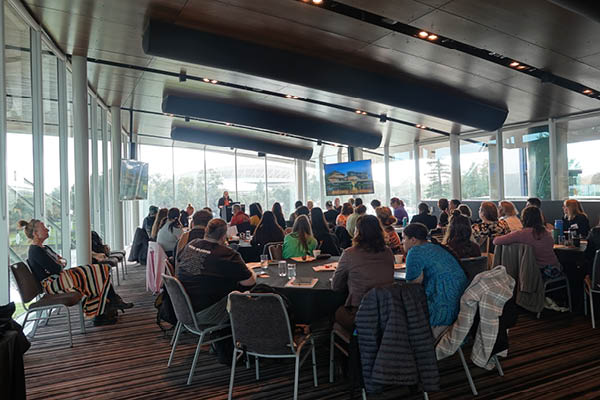 Photo from the back of the room, over the crowd of PhD scholars listening to Professor Andrews