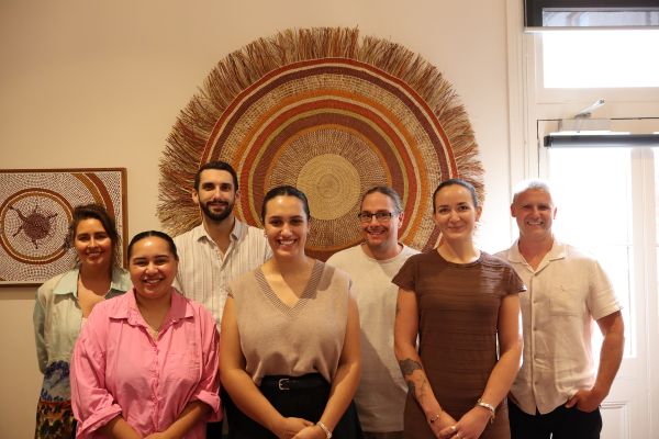 group of Indigenous PhD students in front of a large circular hanging