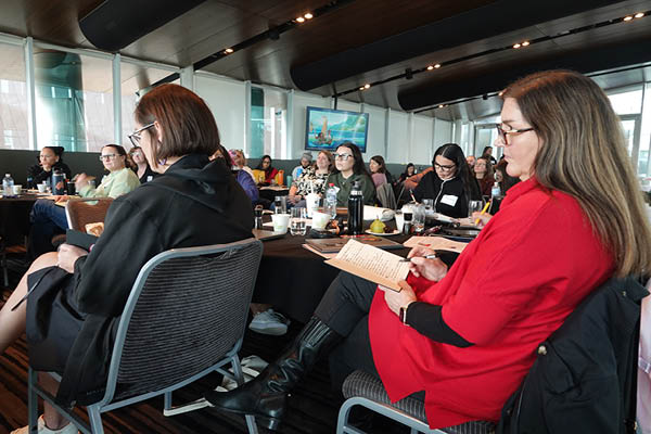Participants taking notes, seated at their table
