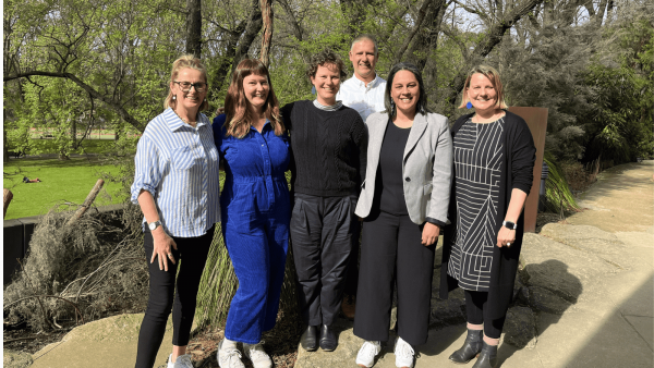 The Melbourne Poche Centre team standing together in front the gardens at Melbourne Museum